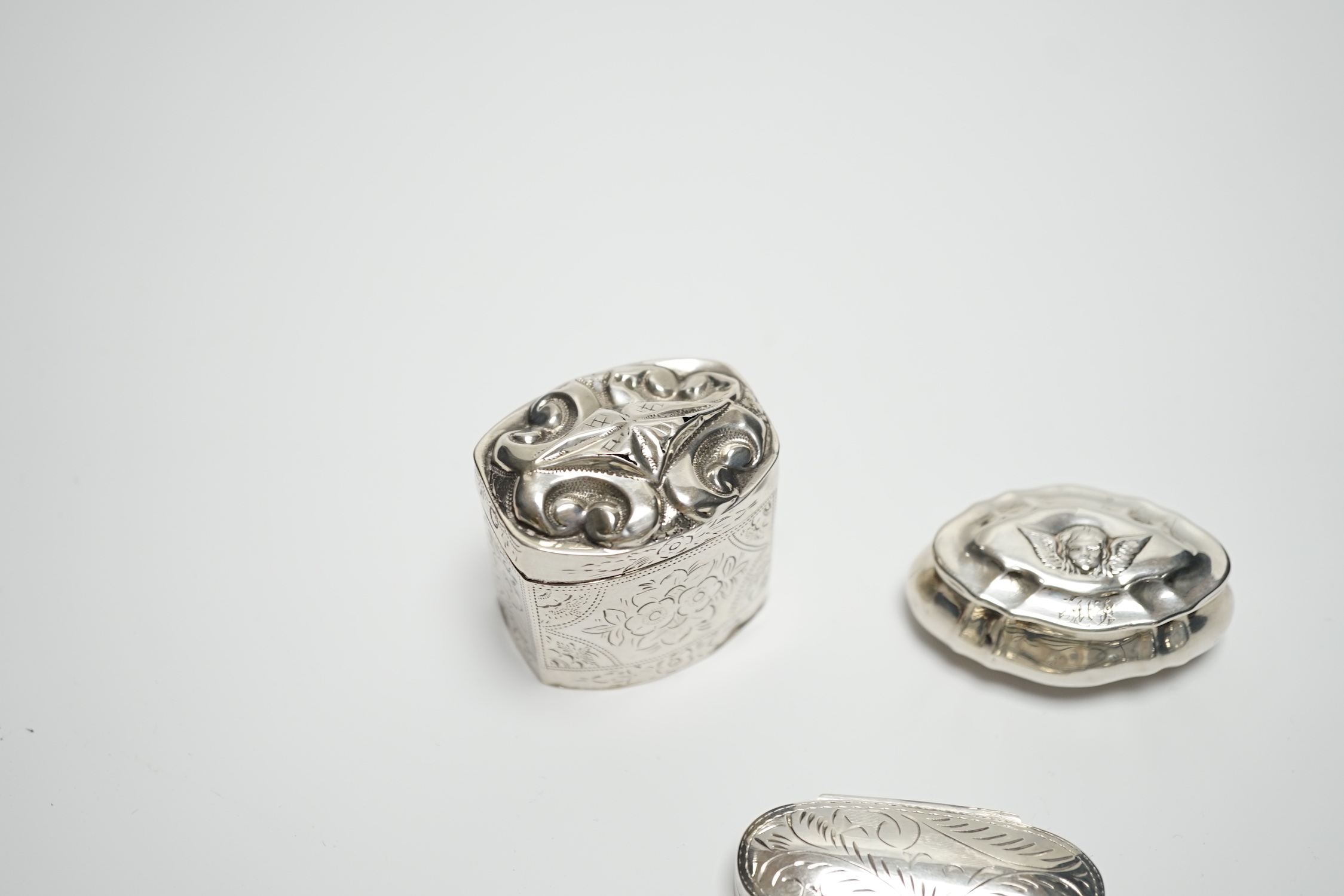A late Victorian silver pill box with Reynold's Angel decorated cover, 47mm, a modern silver pill box and a Dutch white metal box.